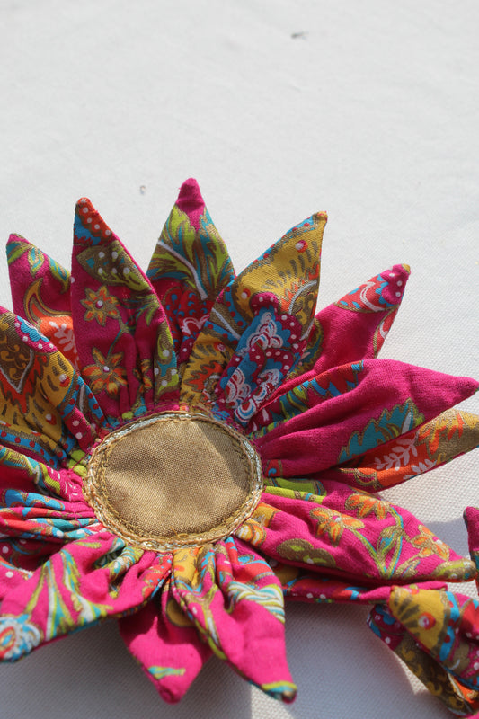 Colorful fabric flower with a gold center on a white background