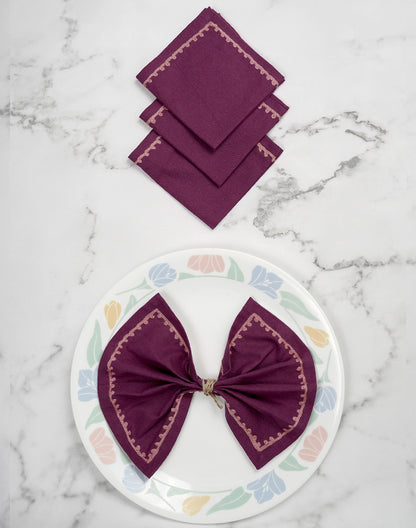 Set of purple napkins on a marble surface with a decorative plate featuring a purple bow.